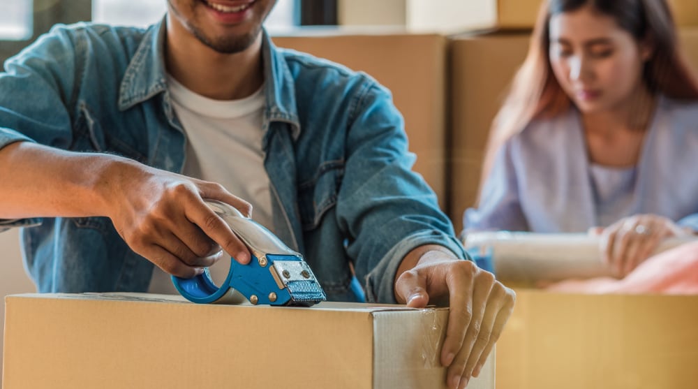 How to Pack for a Move — A Complete Guide closeup asian young couple packing big cardboard b 2021 08 30 06 50 59 utc
